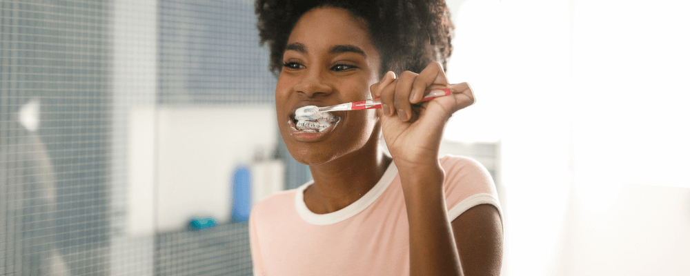 Girl brushing her teeth in the mirror. Following dental tips